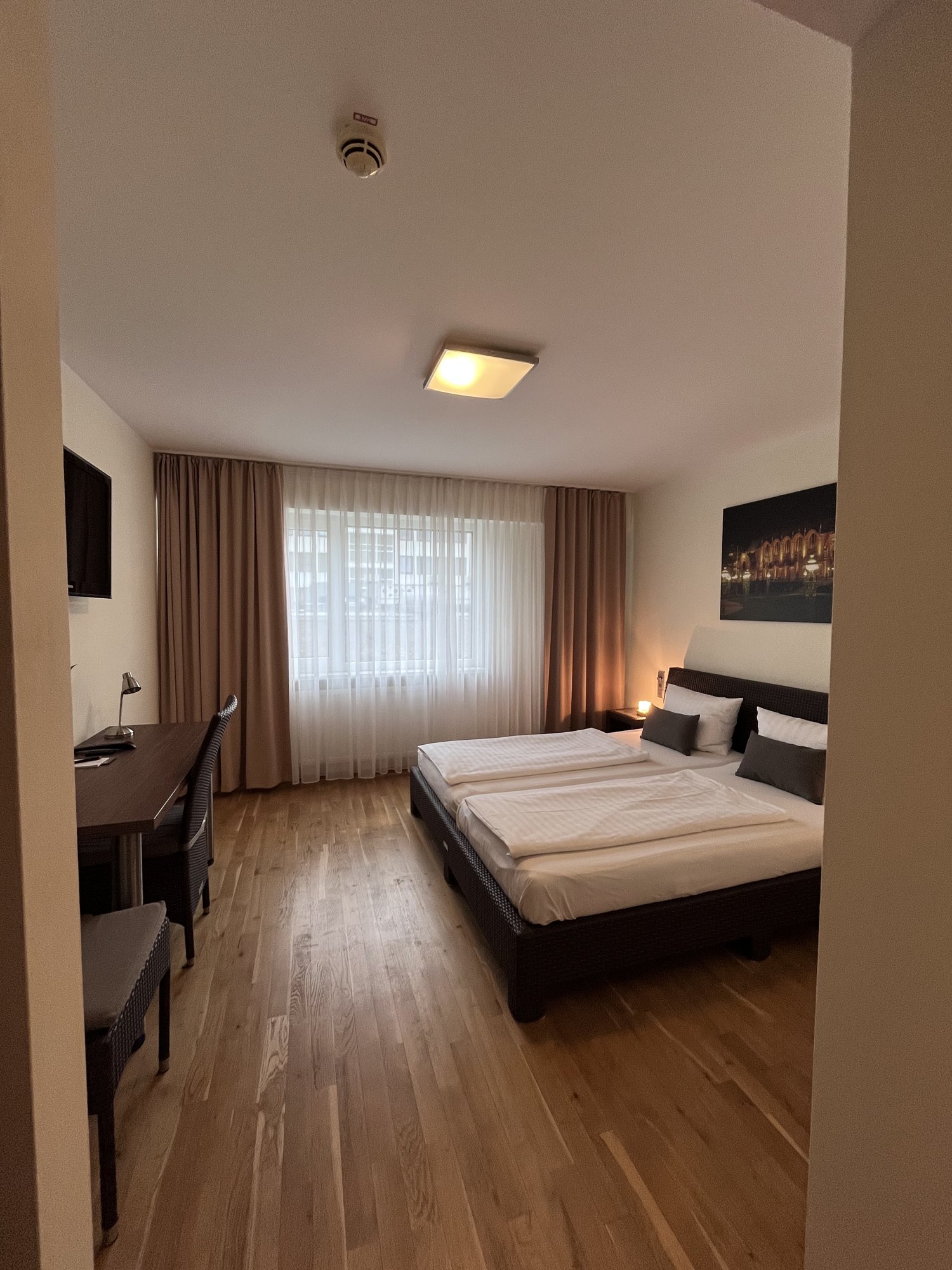 Schlafbereich mit Doppelbett, Vorhängen und Arbeitsplatz